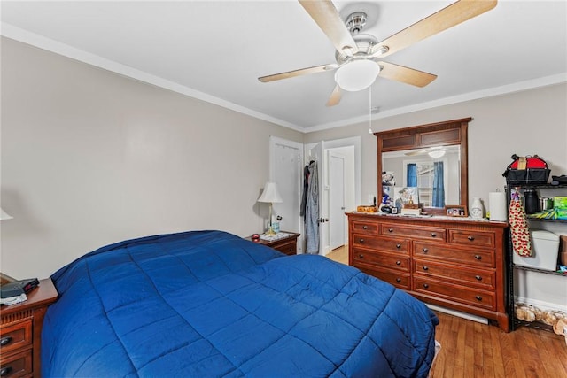 bedroom featuring a ceiling fan, crown molding, and light wood-style floors