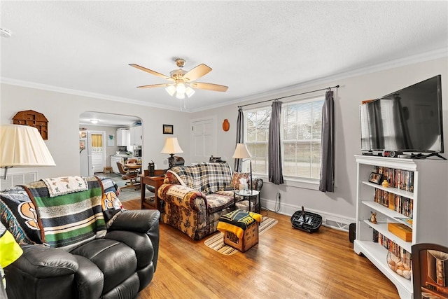 living room with a textured ceiling, wood finished floors, arched walkways, crown molding, and baseboards