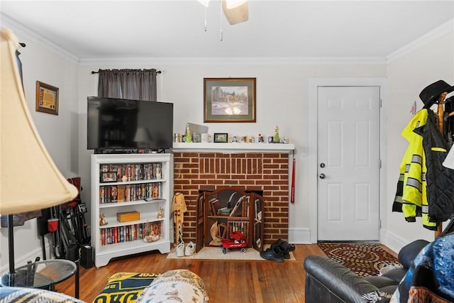 living room with a brick fireplace, wood finished floors, and crown molding