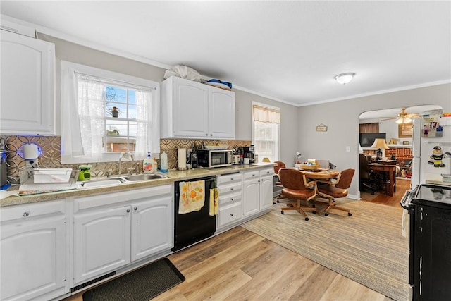 kitchen featuring black appliances, light wood-style floors, a wealth of natural light, and a sink