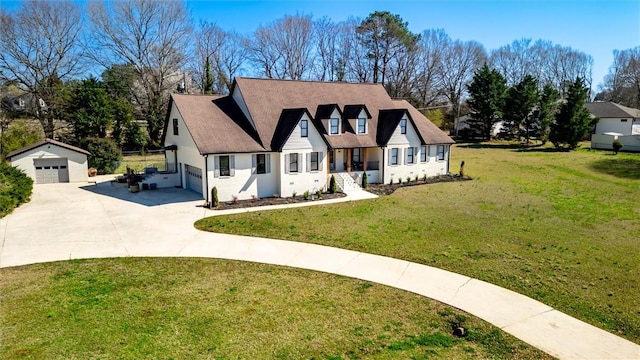 view of front of home with an outbuilding, concrete driveway, a garage, and a front yard