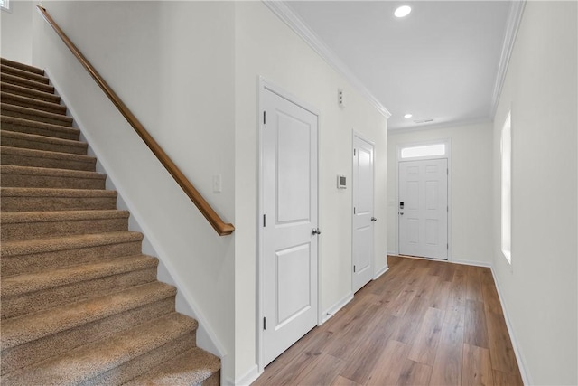 interior space with stairs, wood finished floors, baseboards, ornamental molding, and recessed lighting