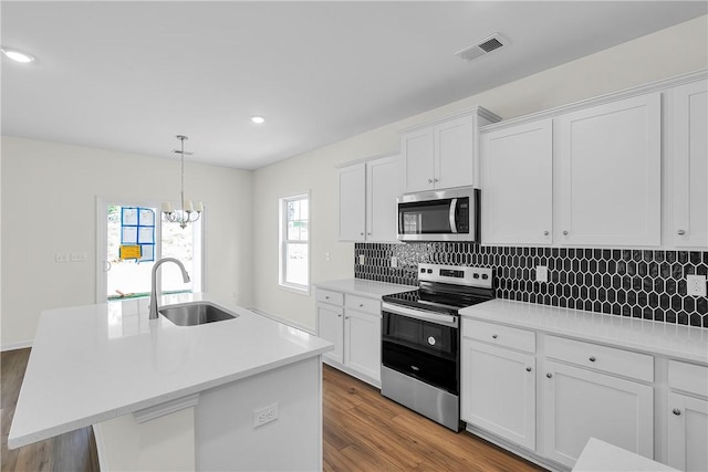 kitchen with a sink, tasteful backsplash, stainless steel appliances, and wood finished floors