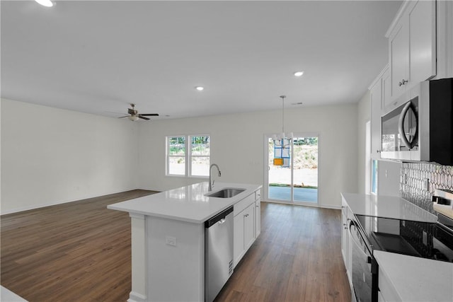 kitchen featuring ceiling fan with notable chandelier, light countertops, a sink, dark wood finished floors, and appliances with stainless steel finishes
