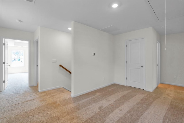 spare room featuring recessed lighting, baseboards, light carpet, and attic access