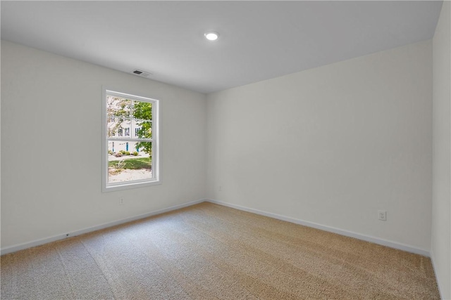 empty room with baseboards, light carpet, and visible vents
