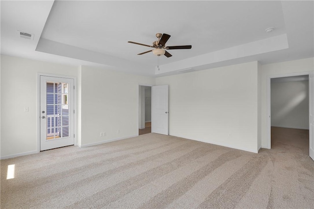 unfurnished room with a ceiling fan, a tray ceiling, and light colored carpet