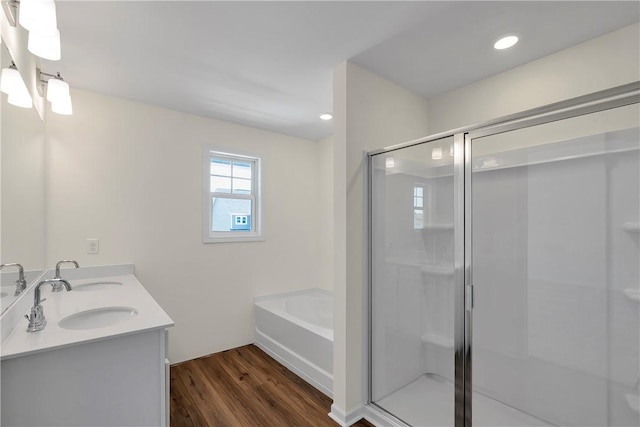 bathroom featuring a sink, a bath, wood finished floors, and a shower stall