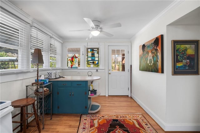 kitchen featuring crown molding, blue cabinetry, light countertops, and light wood-type flooring