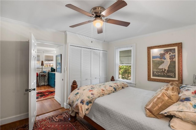 bedroom featuring a ceiling fan, baseboards, wood finished floors, ornamental molding, and a closet