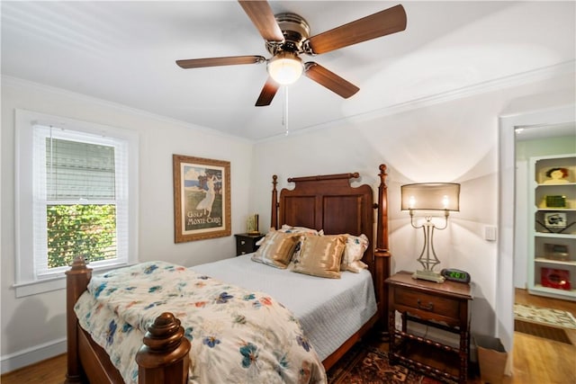 bedroom with baseboards, wood finished floors, ornamental molding, and a ceiling fan