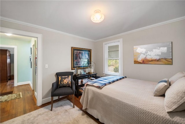 bedroom featuring baseboards, light wood-style flooring, and crown molding