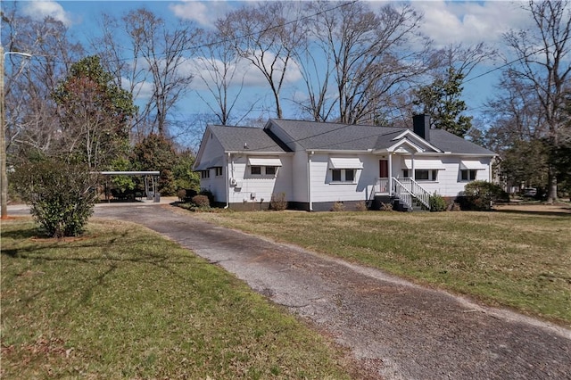 exterior space featuring a yard, a carport, a chimney, and driveway