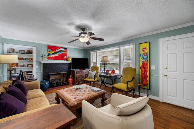 living area with a fireplace, ceiling fan, wood finished floors, and ornamental molding