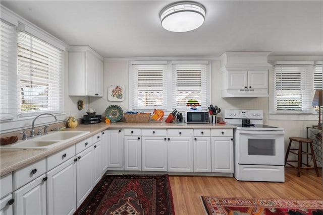 kitchen with under cabinet range hood, light countertops, light wood-style floors, white electric range, and a sink