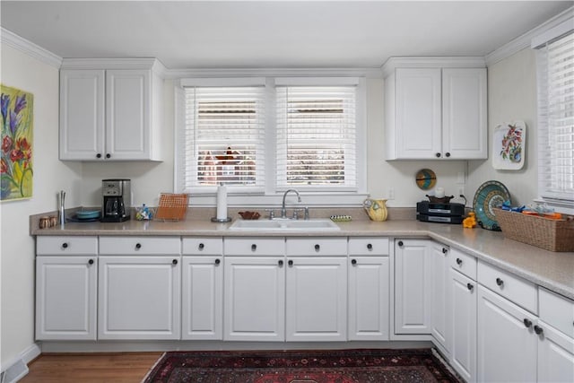 kitchen with a sink, visible vents, light countertops, and white cabinetry