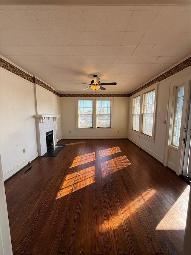 unfurnished living room with a wealth of natural light, dark wood finished floors, a fireplace, and ornamental molding