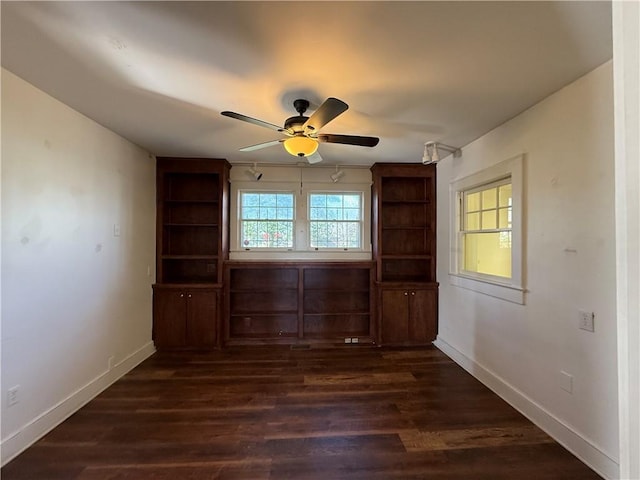 spare room with dark wood finished floors, baseboards, and a wealth of natural light