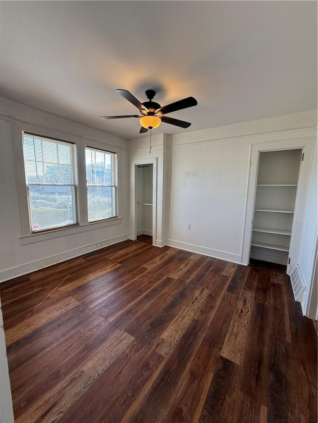 unfurnished bedroom featuring baseboards, dark wood-type flooring, and ceiling fan