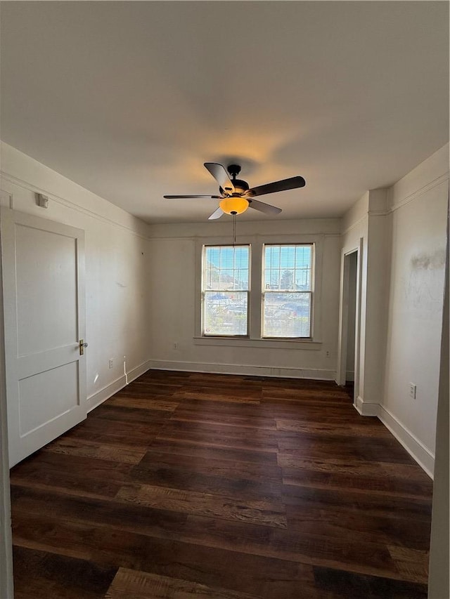 empty room featuring baseboards, dark wood-type flooring, and a ceiling fan