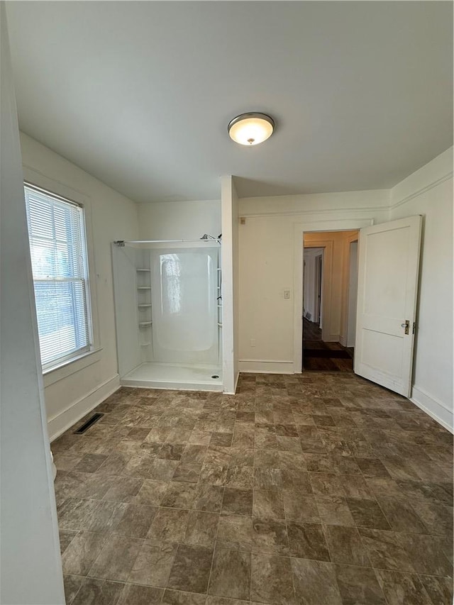 interior space with baseboards, visible vents, and a shower with door