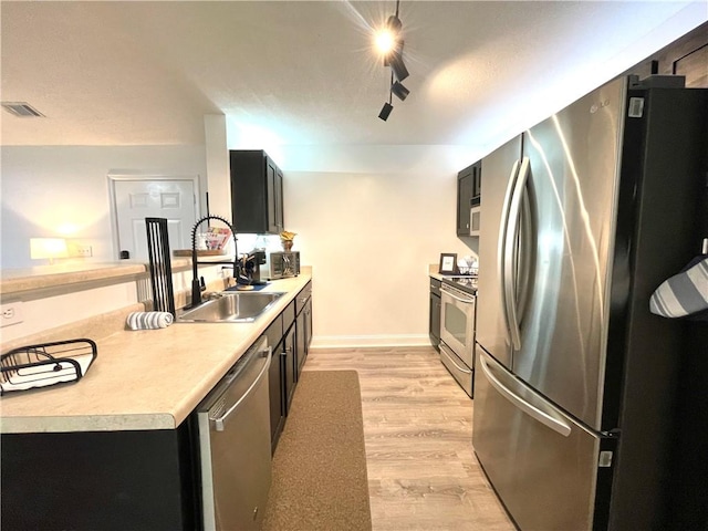 kitchen featuring visible vents, light wood-style flooring, a sink, stainless steel appliances, and light countertops