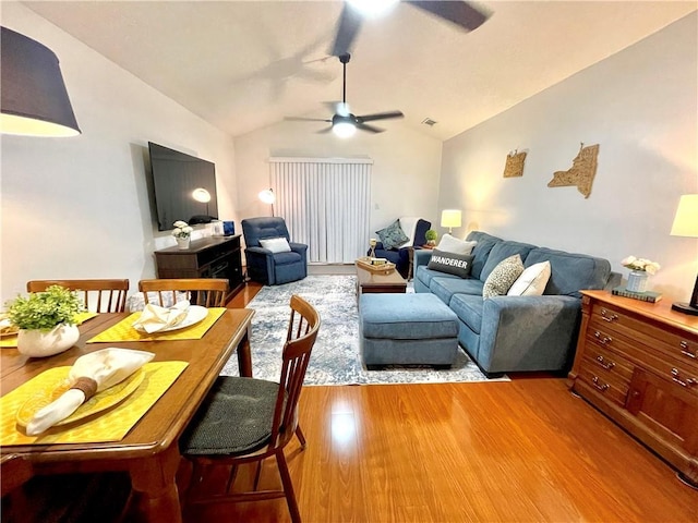 living area featuring lofted ceiling, visible vents, light wood-type flooring, and ceiling fan