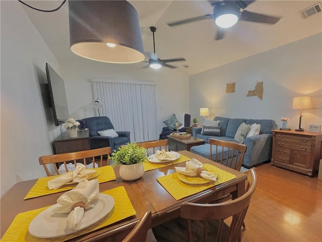 dining area with light wood finished floors, visible vents, a ceiling fan, and lofted ceiling