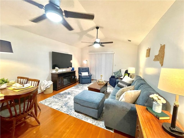 living room featuring vaulted ceiling, visible vents, a ceiling fan, and wood finished floors