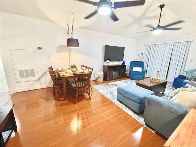 living area featuring baseboards, wood finished floors, visible vents, and ceiling fan