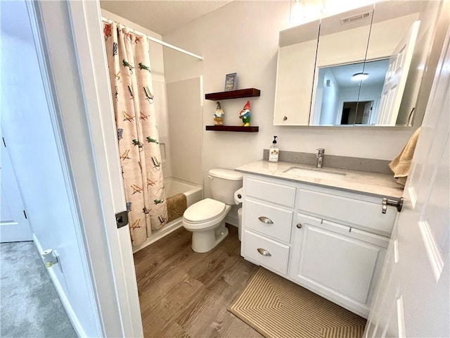 bathroom featuring visible vents, toilet, wood finished floors, shower / bath combination with curtain, and vanity