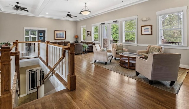 living area featuring beamed ceiling, ornamental molding, a ceiling fan, wood finished floors, and baseboards