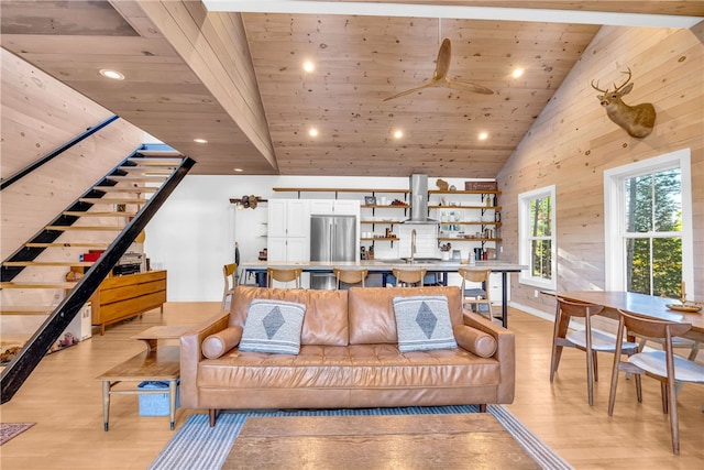 living room with wood walls, wood ceiling, light wood-style floors, high vaulted ceiling, and a ceiling fan