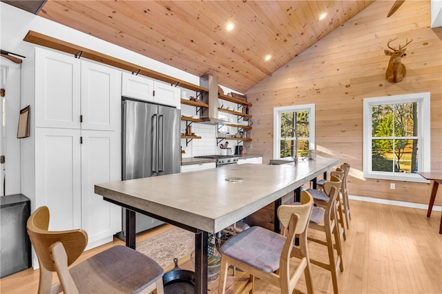 dining room featuring wooden walls, lofted ceiling, recessed lighting, light wood-style flooring, and wooden ceiling