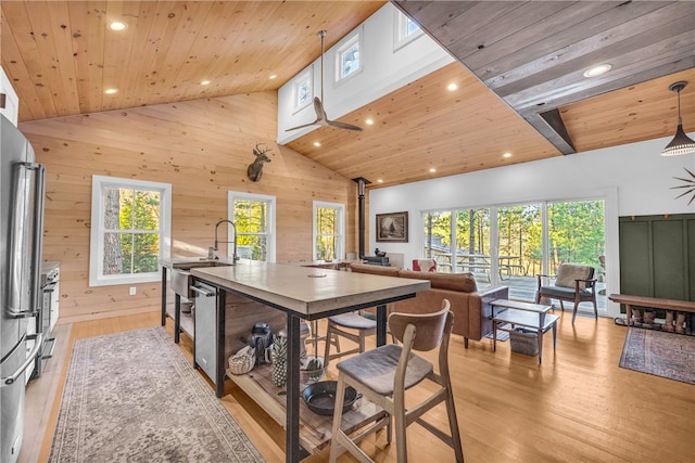 kitchen featuring a wood stove, plenty of natural light, wood walls, wooden ceiling, and light wood-type flooring