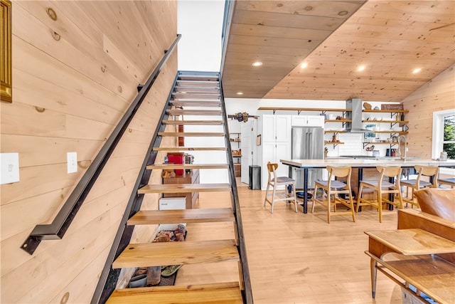 stairs featuring wood finished floors, recessed lighting, wooden walls, lofted ceiling, and wood ceiling