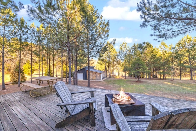 wooden deck with an outbuilding, a fire pit, and a lawn