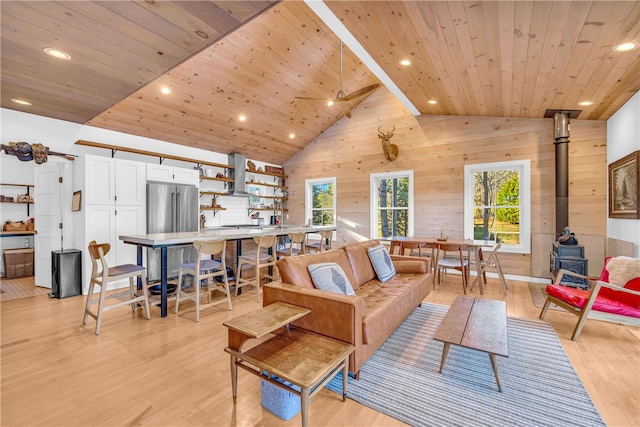 living room with light wood-style flooring, a healthy amount of sunlight, wooden ceiling, and a wood stove