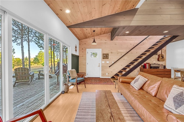 living room with light wood finished floors, vaulted ceiling with beams, wood walls, stairs, and wooden ceiling