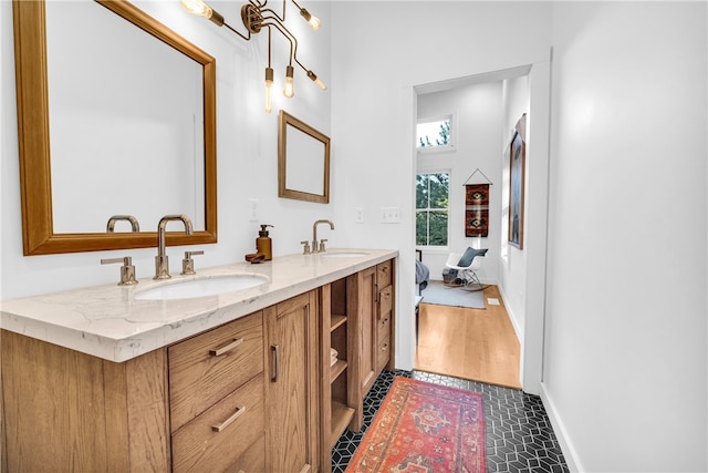 bathroom featuring a sink, connected bathroom, baseboards, and double vanity