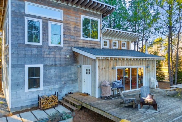 back of house featuring a wooden deck, an outdoor fire pit, and roof with shingles