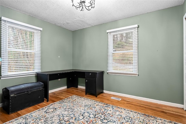 office featuring wood finished floors, a healthy amount of sunlight, baseboards, and visible vents