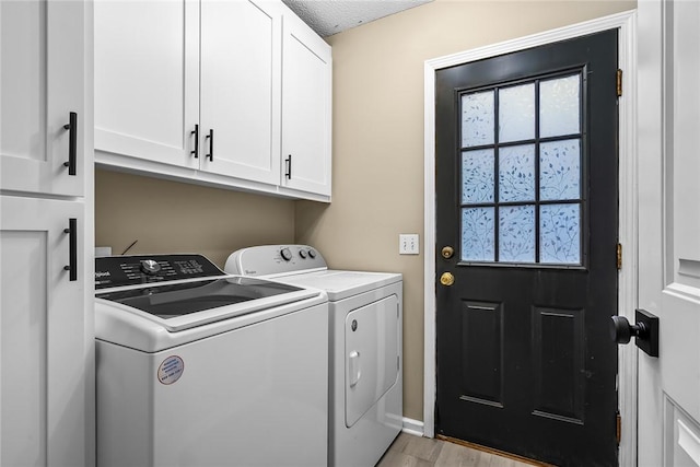 washroom featuring cabinet space, independent washer and dryer, light wood finished floors, and a textured ceiling