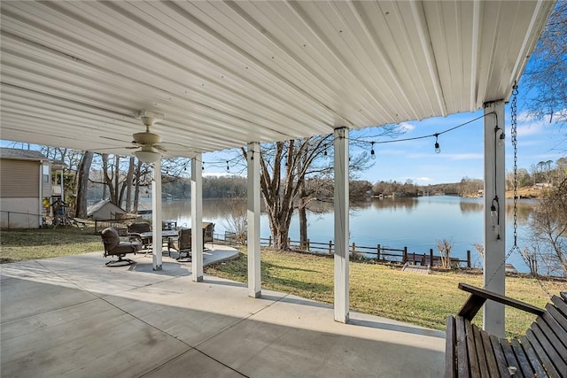 view of patio / terrace featuring fence, outdoor dining area, a ceiling fan, and a water view