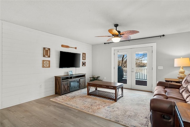 living area with light wood finished floors, french doors, a textured ceiling, and ceiling fan