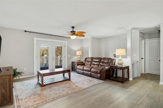 living area with radiator, baseboards, attic access, french doors, and wood finished floors