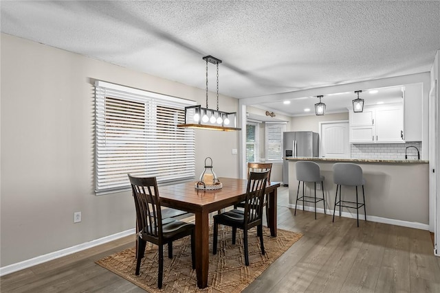 dining space with dark wood finished floors, a textured ceiling, and baseboards