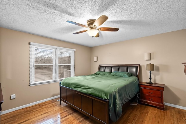 bedroom with a textured ceiling, a ceiling fan, baseboards, and hardwood / wood-style flooring