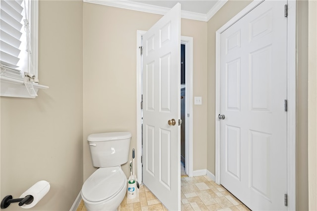 bathroom featuring stone finish flooring, baseboards, toilet, and crown molding