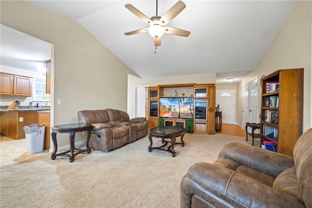 living area featuring baseboards, light carpet, a ceiling fan, and vaulted ceiling